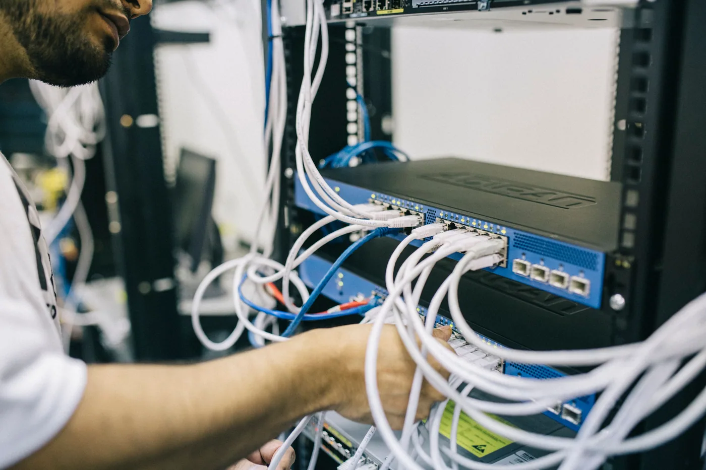 A technician connecting network cables in an equipment rack.