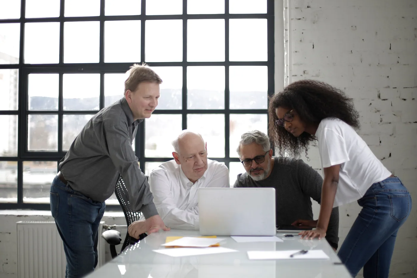Four colleagues reviewing plans and a laptop together at a table.
