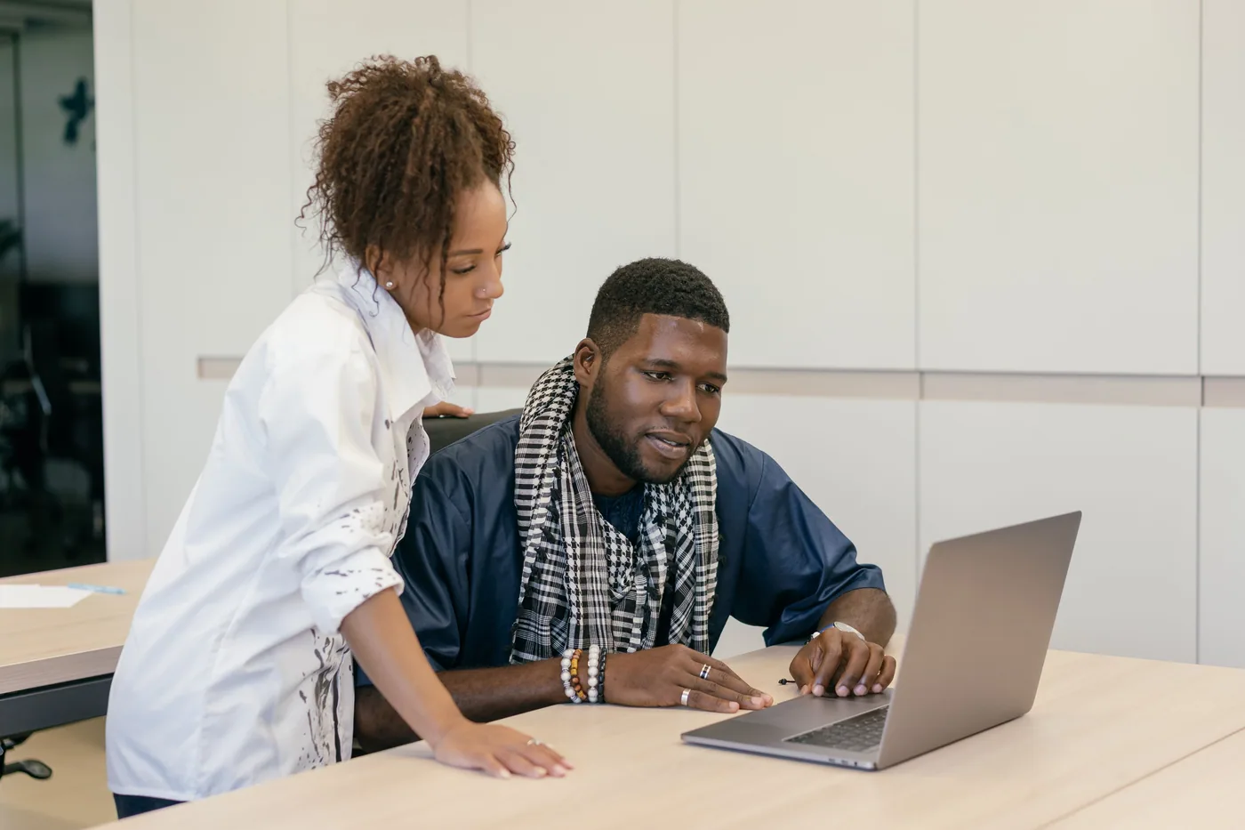 Two colleagues working through a question together at a laptop.